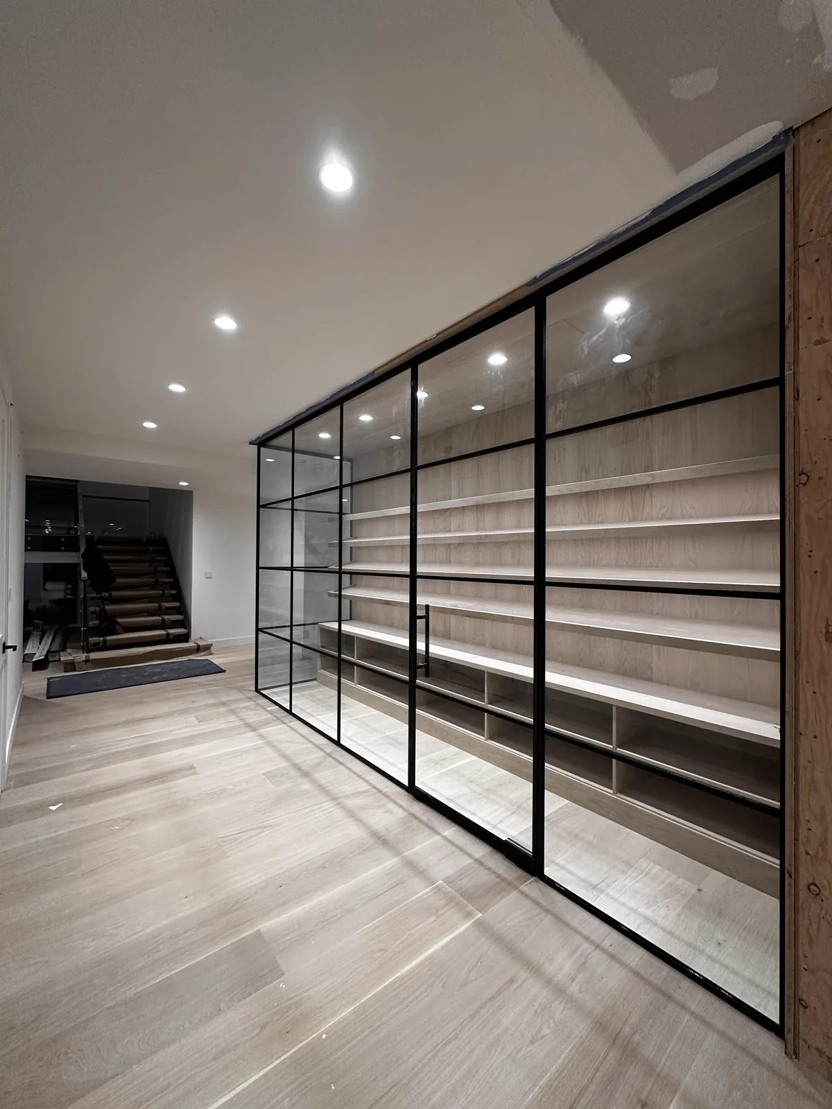 L-shaped glass partition wall with single swing door by WiseGlass NY
